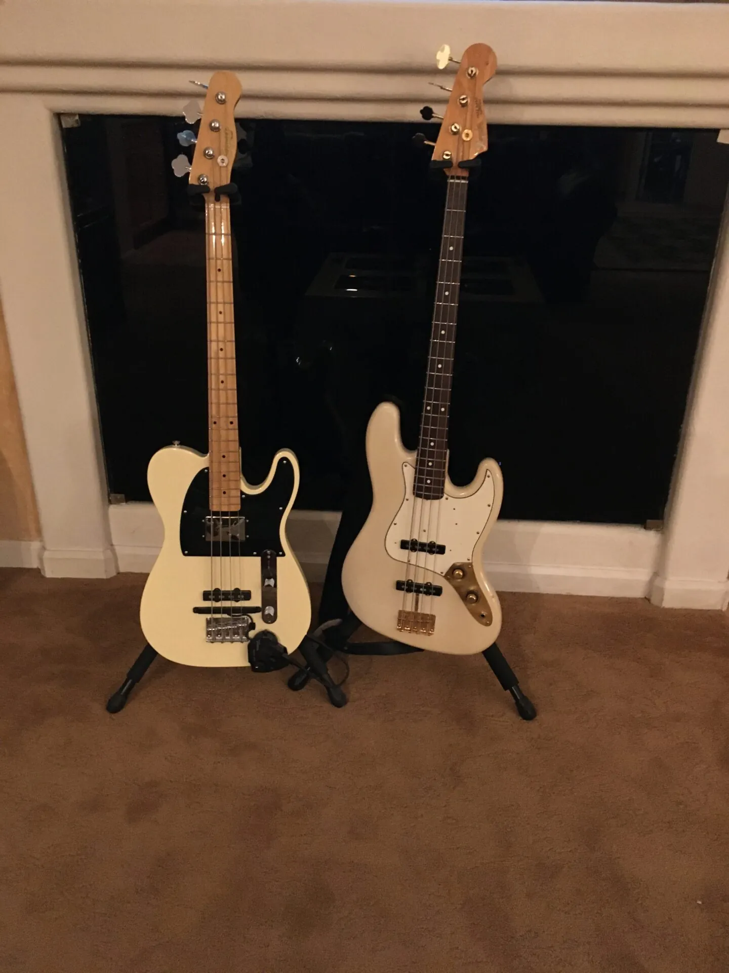 Two Fender-style basses with maple fingerboards on stands