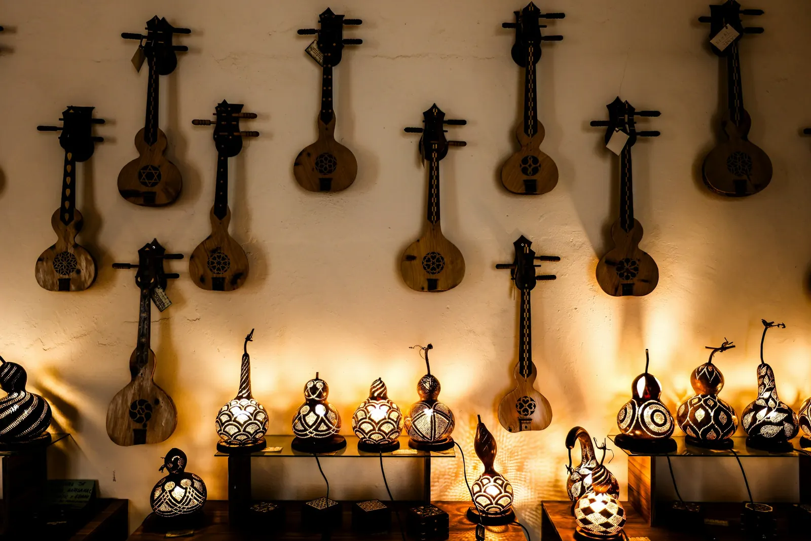 Mandolins hanging on a warmly lit wall above glowing lamps