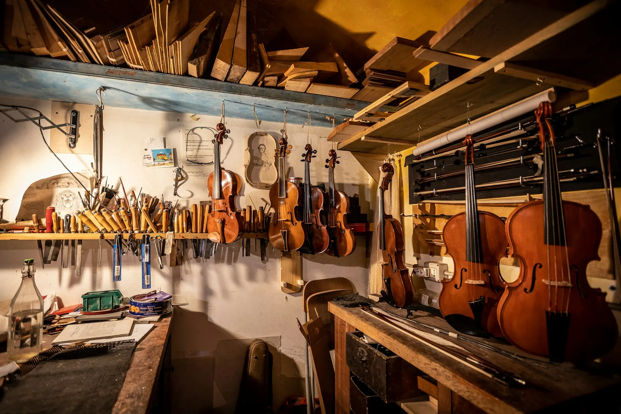 A luthier’s workshop with violins, cellos and guitars hanging above the workbenches