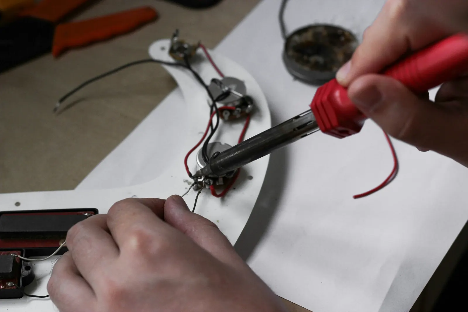 Soldering the wiring on an electric guitar’s control plate