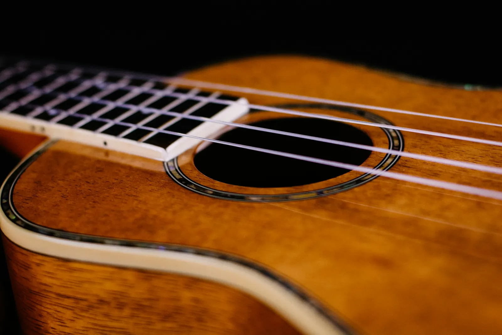 A ukulele’s soundhole, strings and fingerboard, close up
