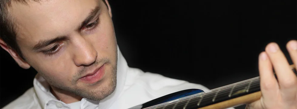 Wesley Wilkerson playing a guitar, looking down at the fretboard